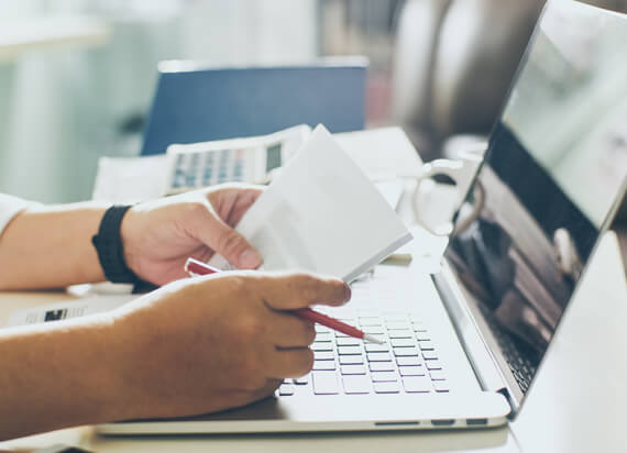 person holding papers over laptop